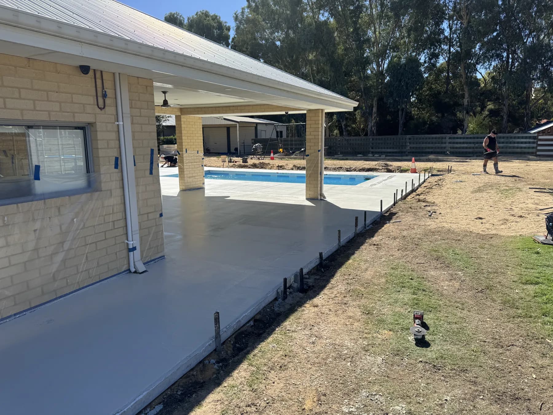 Fresh concrete pool surround being screeded and prepared for finishing